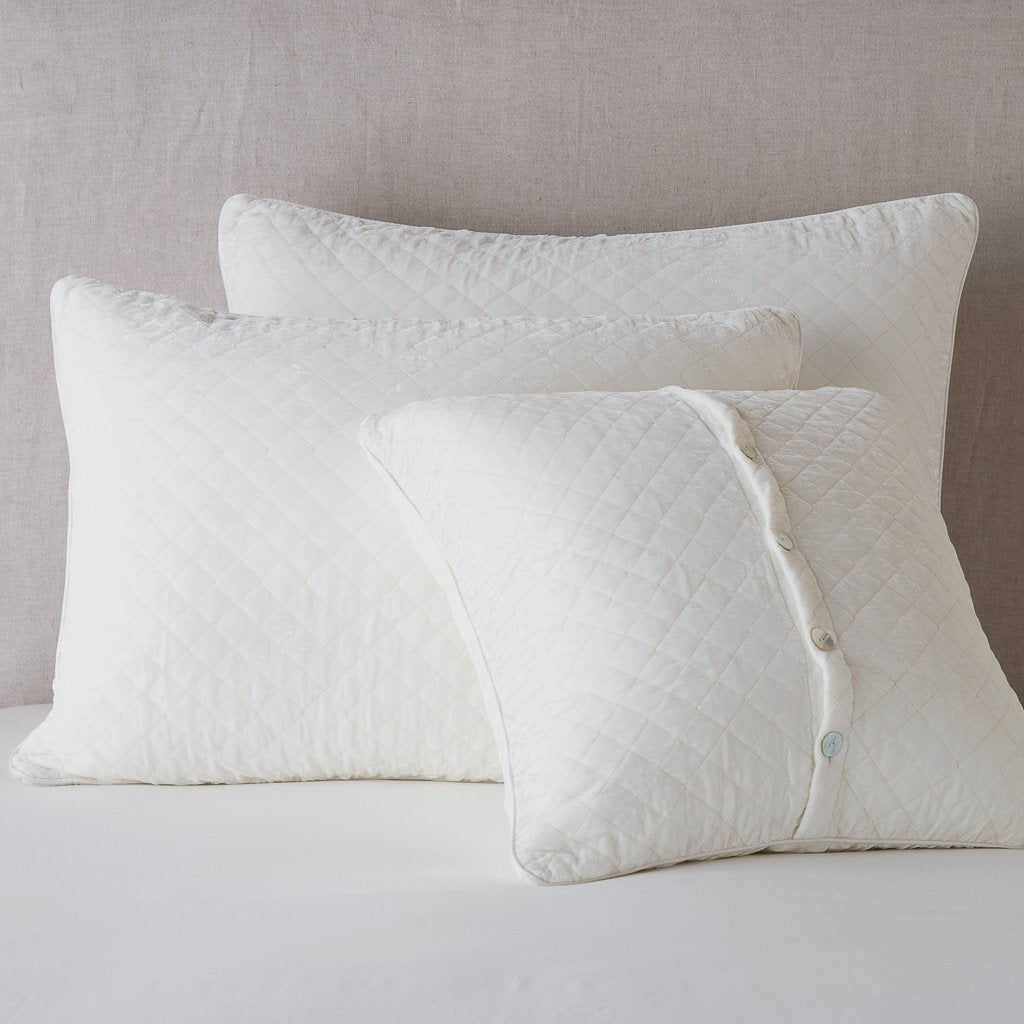 Winter White: shams leaning upright against a neutral headboard. One sham is backwards to showcase the shimmering shell button closure.