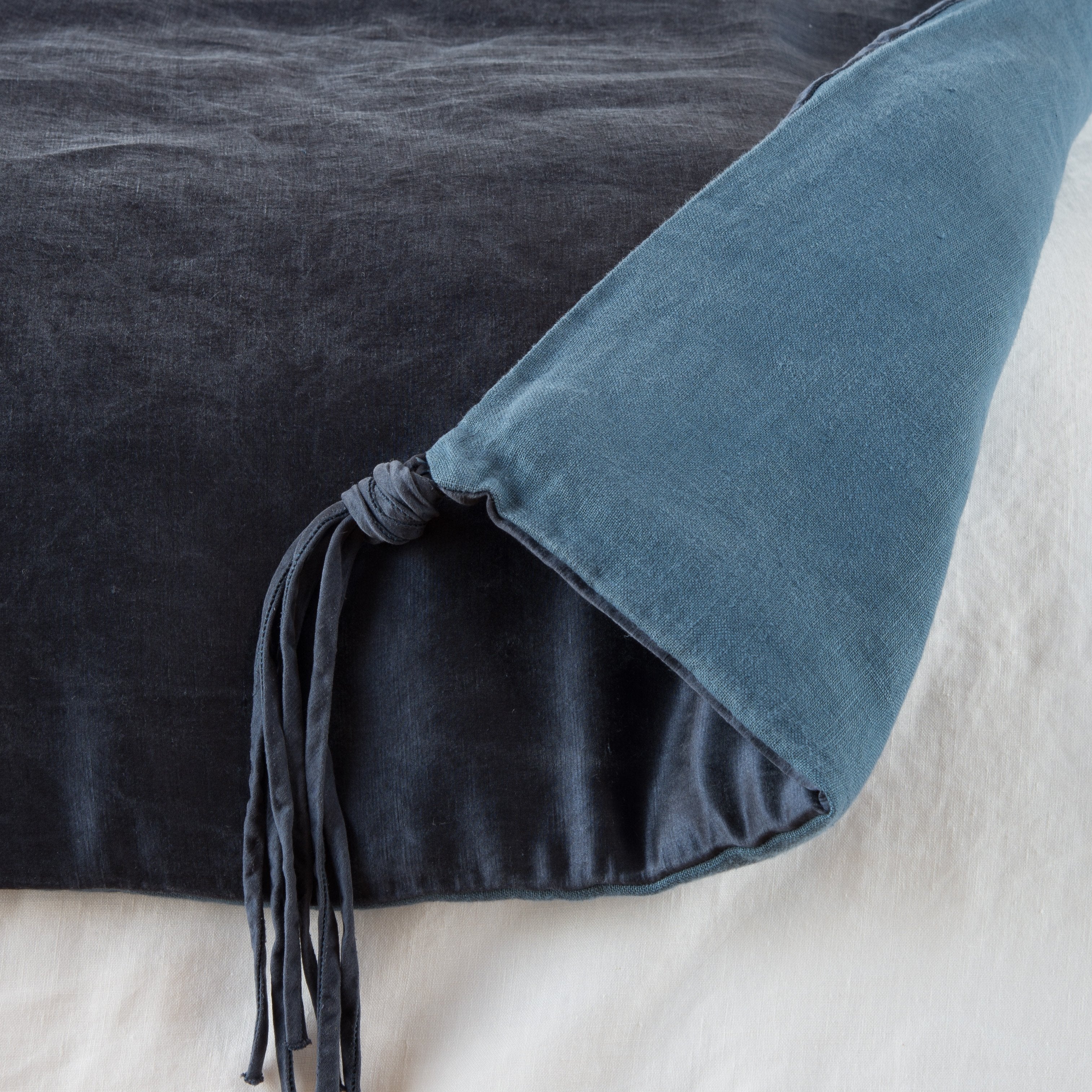 Midnight: Close up of blanket, with a corner turned back to showcase the midweight linen back and corner tassel - overhead view.