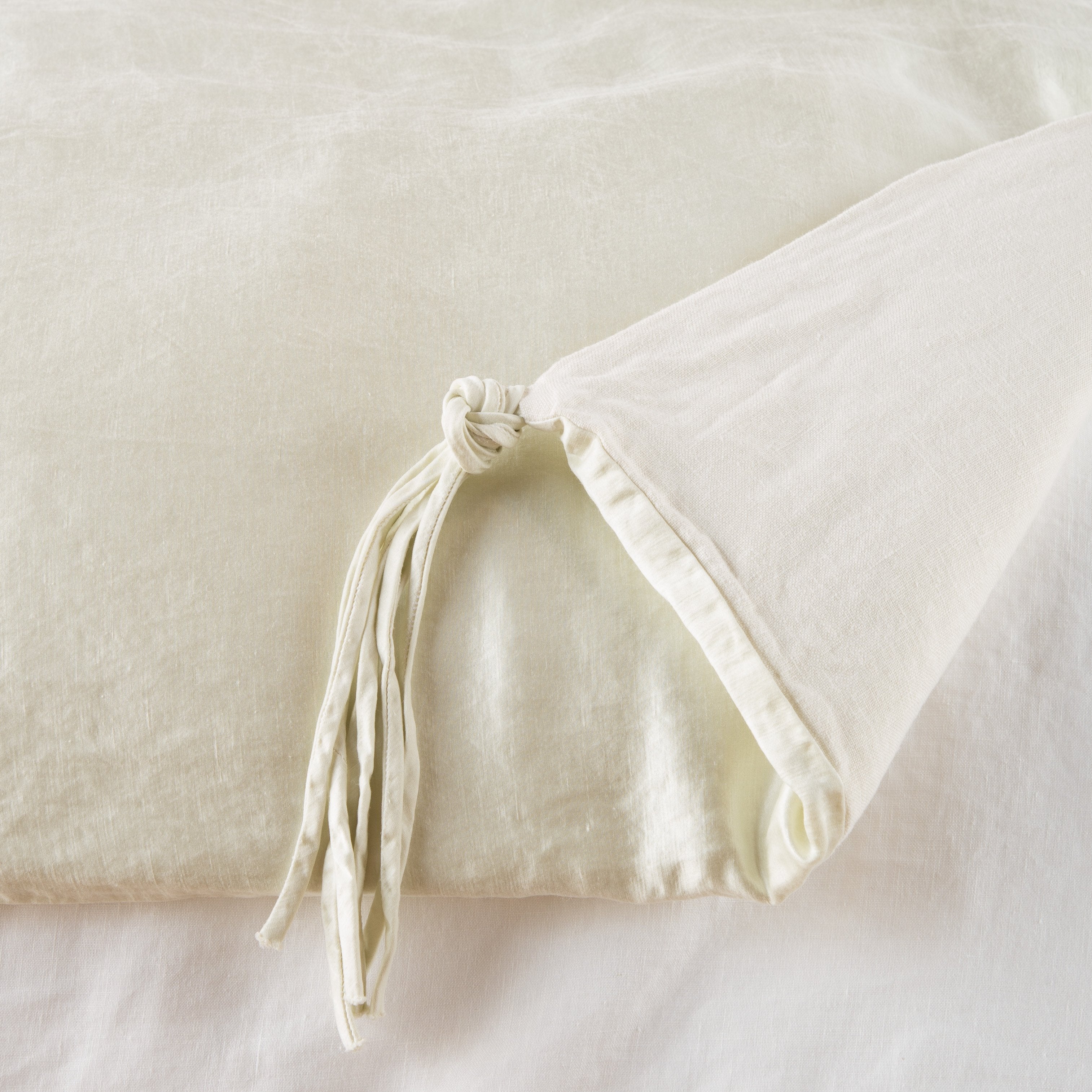 Parchment: Close up of blanket, with a corner turned back to showcase the midweight linen back and corner tassel - overhead view.