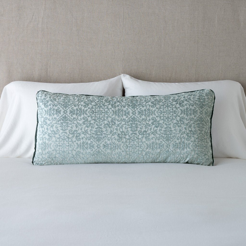 Eucalyptus: 16x36 pillow leaning upright against white sleeping pillows on a neutral headboard.