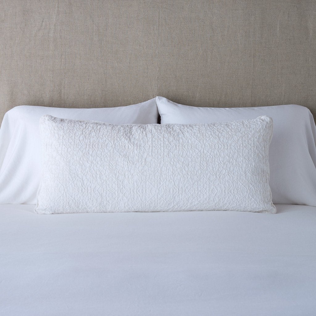 White: 16x36 pillow leaning upright against white sleeping pillows on a neutral headboard.