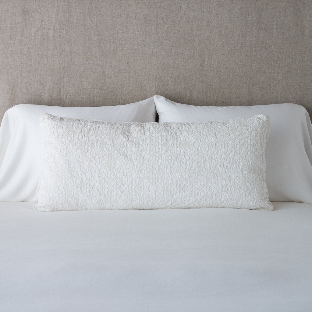 Winter White: 16x36 pillow leaning upright against white sleeping pillows on a neutral headboard.
